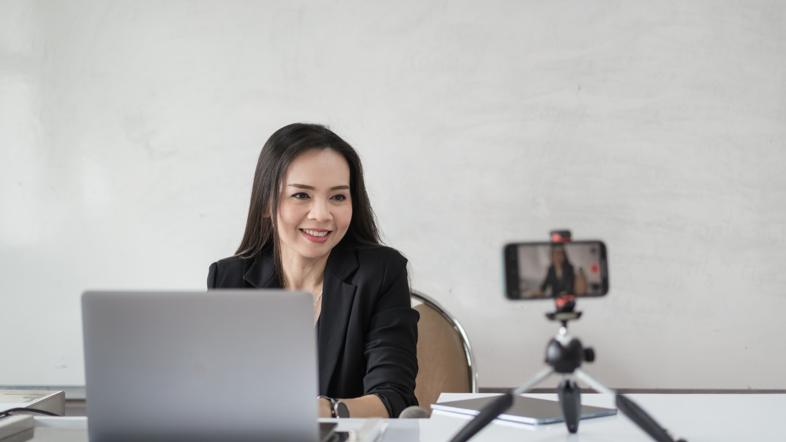 a woman sitting at a table with a laptop and a camera
